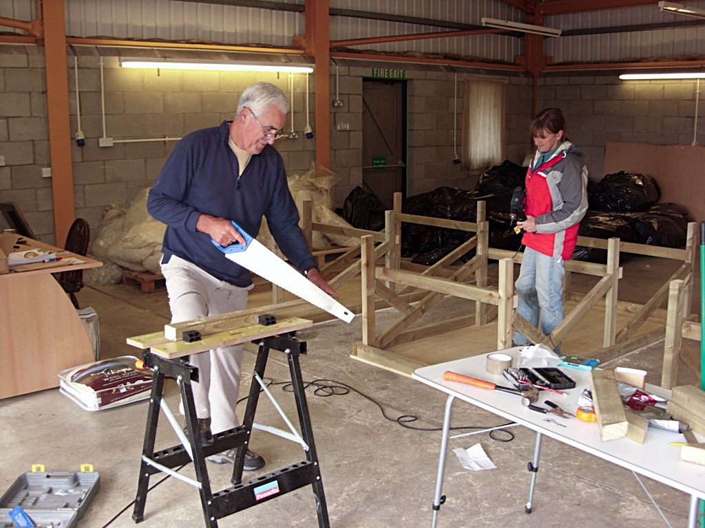 Roger and Lesley sawing and building the first work tables